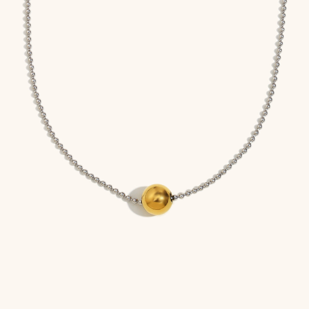 Close-up of gold bead pendant on dainty silver ball chain