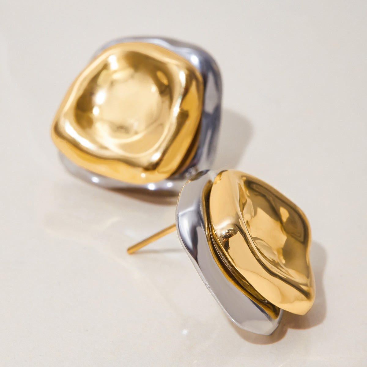 close-up side angle of minimalist dome stud earrings in silver and gold