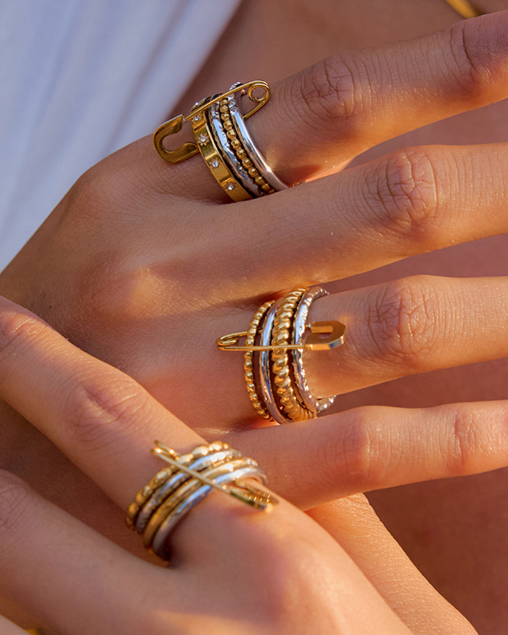 Close-up of a hand wearing multiple gold and silver rings.