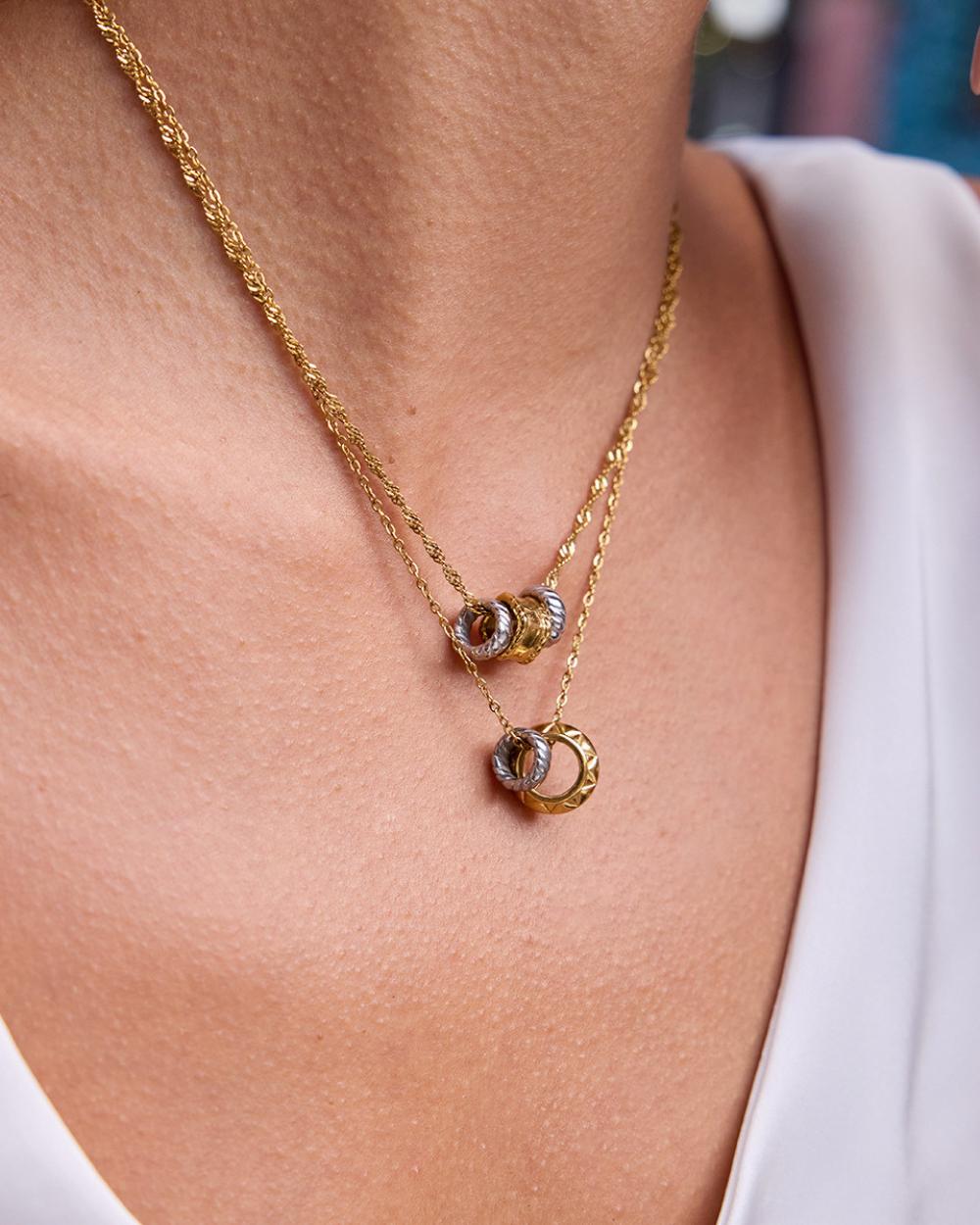 Gold necklace with a unique pendant on a person wearing a white top.