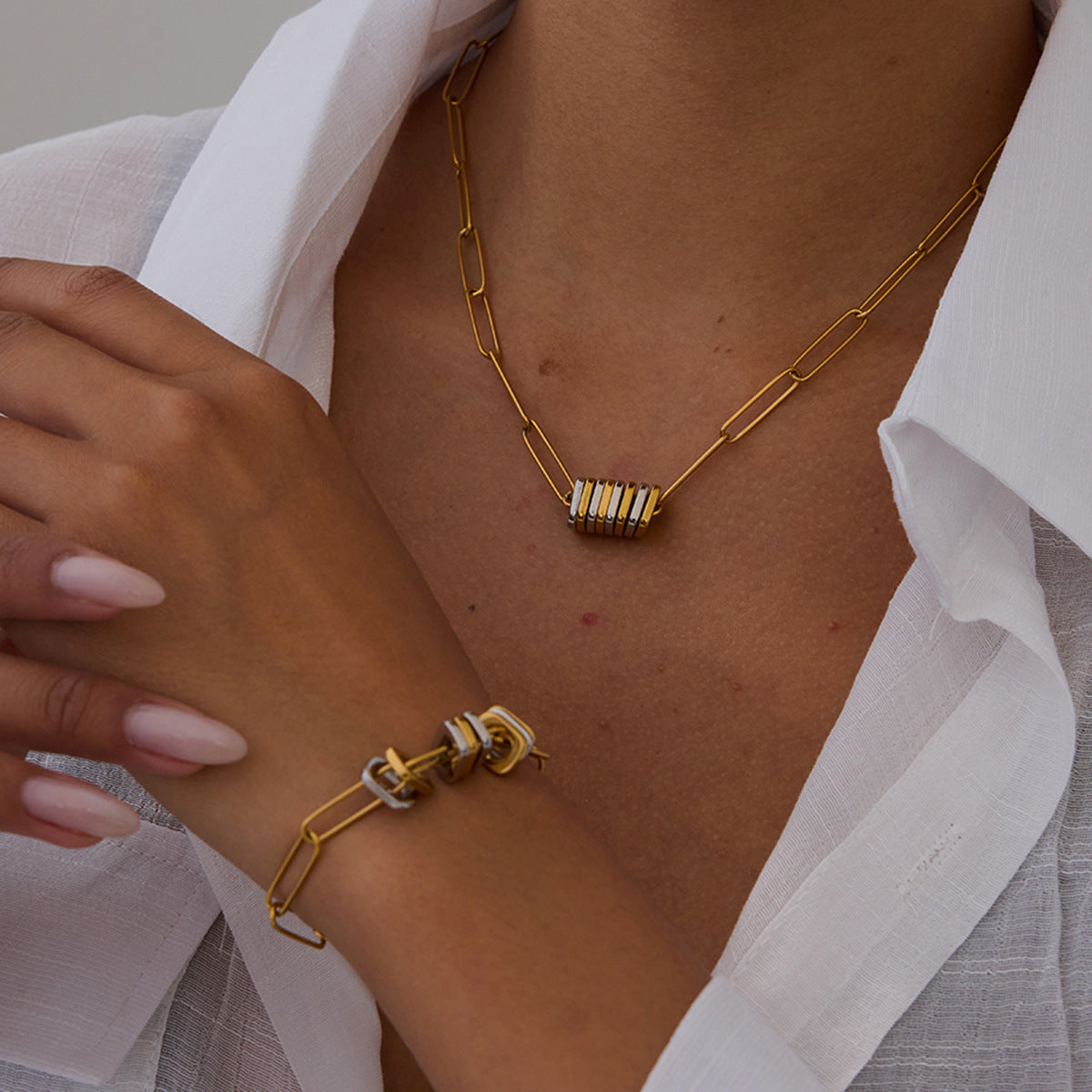 Gold and silver link chain jewelry set worn by a woman in a white blouse, highlighting the mixed metal statement design.