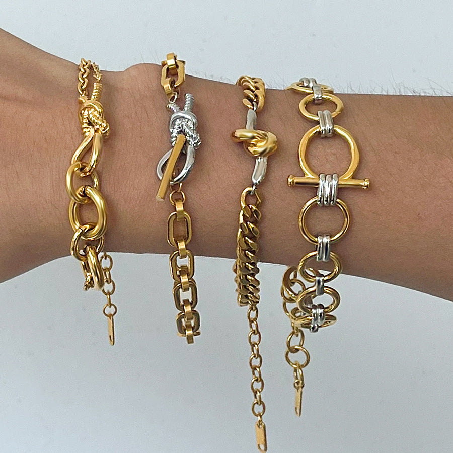 Multiple gold and silver chain bracelets on a wrist against a white background