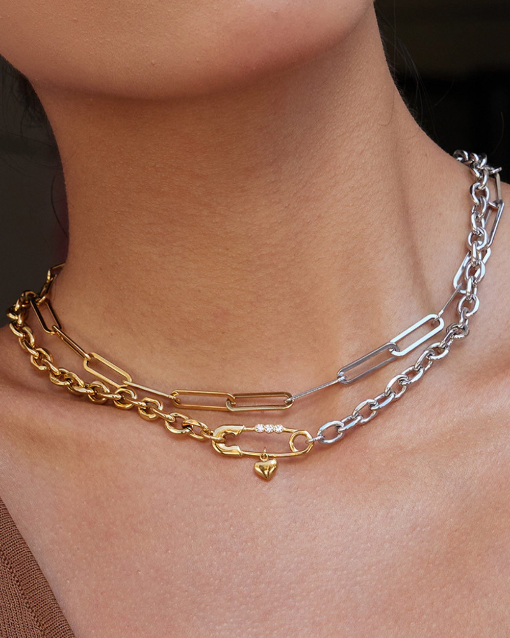 Two chain necklaces, one gold and one silver, on a person's neck.