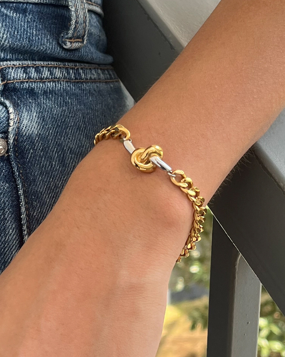Gold chain bracelet on a wrist with a blurred background