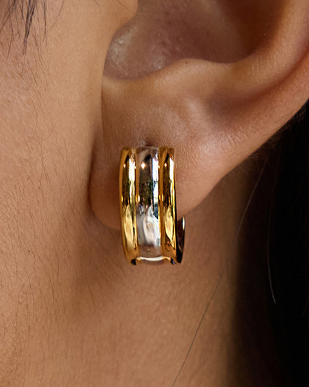 Gold hoop earring worn on an ear