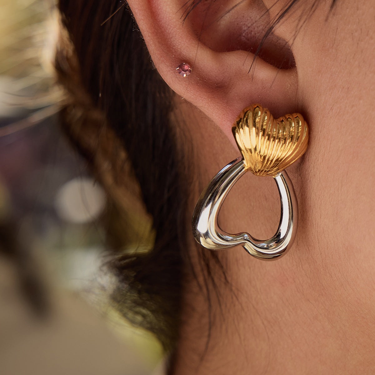 Model wearing heart-shaped drop earrings in outdoor daylight scene