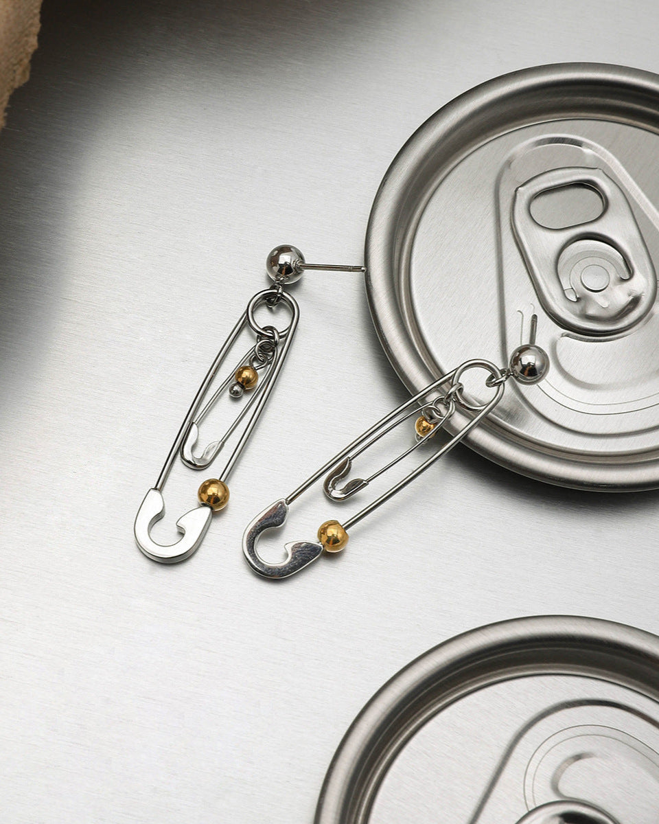 Silver and gold safety pin earrings paired with soda can lid for grunge aesthetic