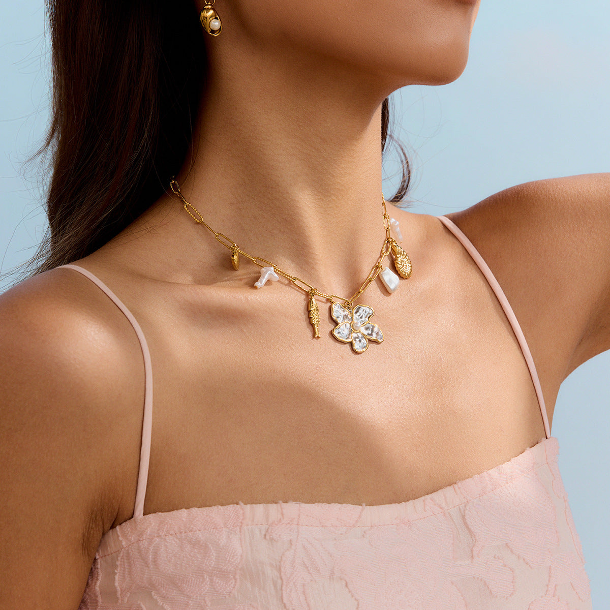 Woman in yellow dress wearing gold beach necklace with hammered flower and ocean charms