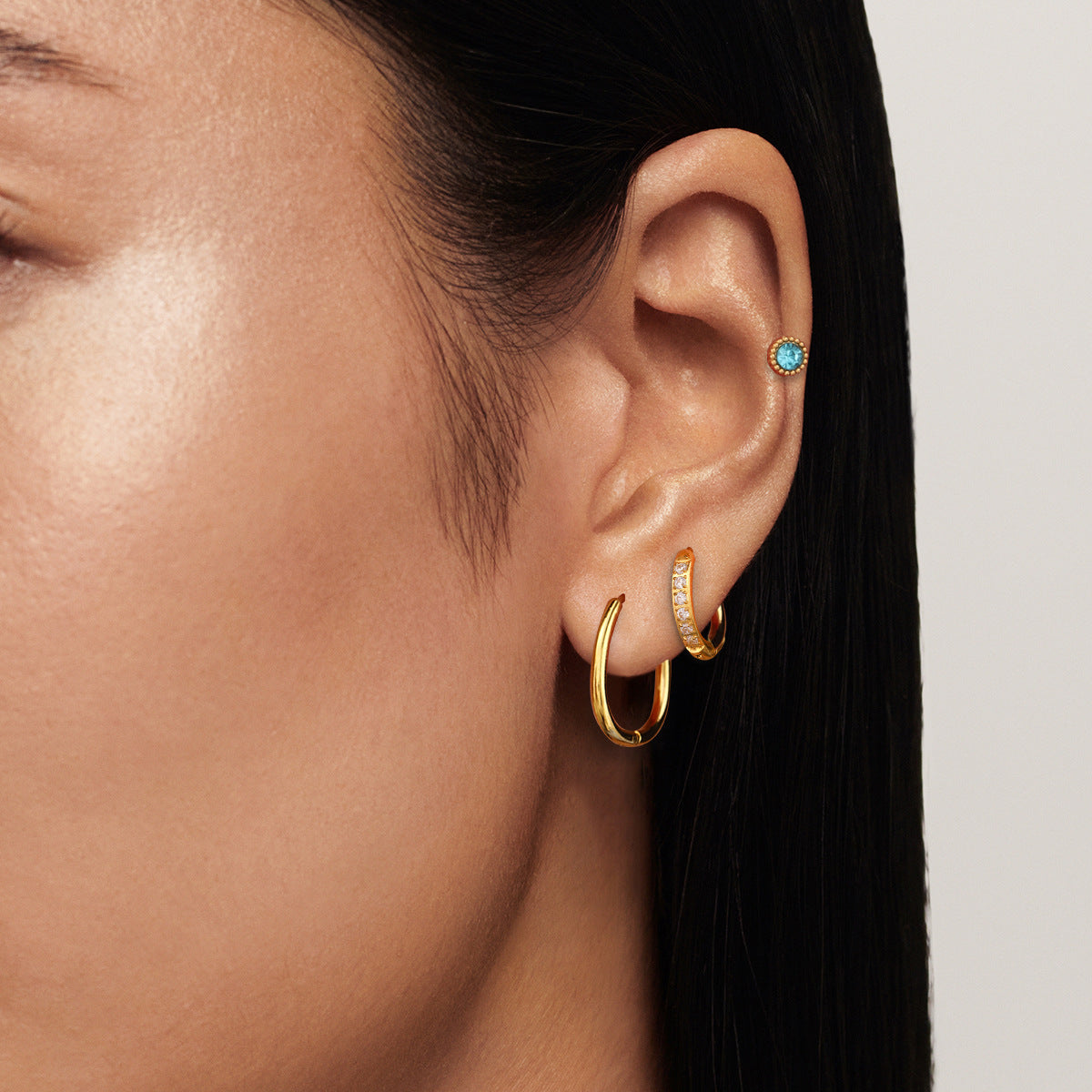 model wearing multi-hoop gold earrings with turquoise stud, stacked earring look