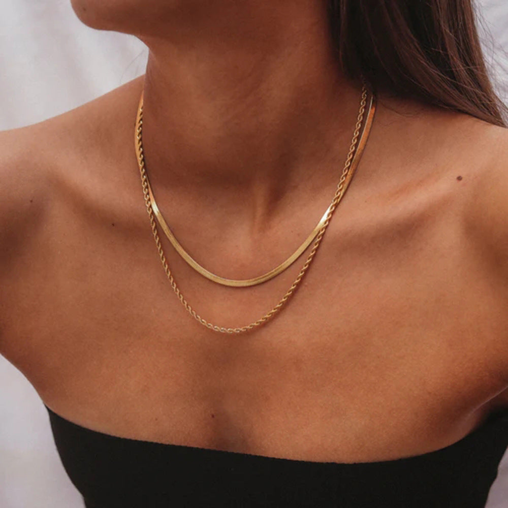 Woman wearing a gold layered necklace with snake and rope chain over bare shoulders