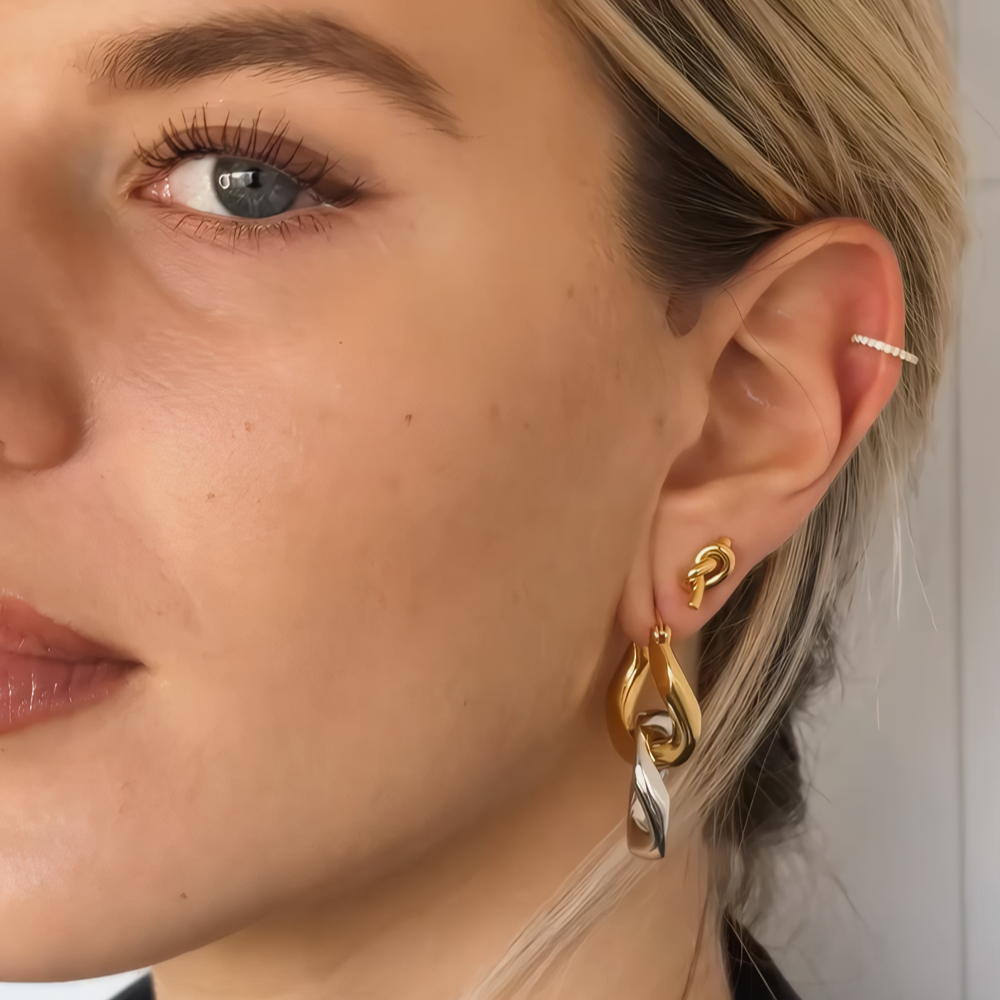 Close-up of woman wearing mixed metal hoop earrings styled with minimal makeup
