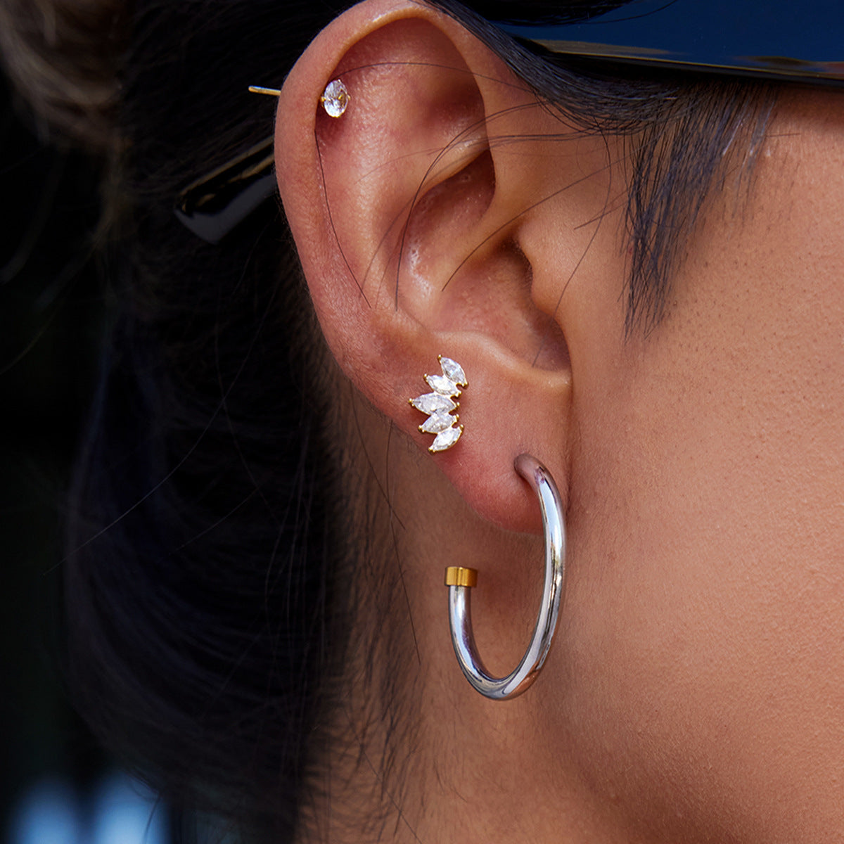 Close-up of an ear with multiple earrings including a silver hoop earring.