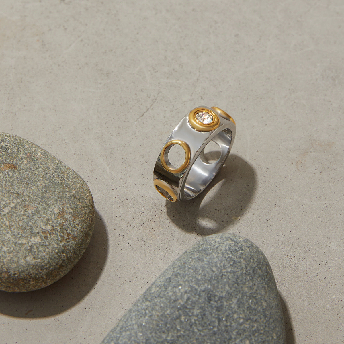 Polished dome ring featuring crystal insets and mixed metal tones, flat lay on concrete