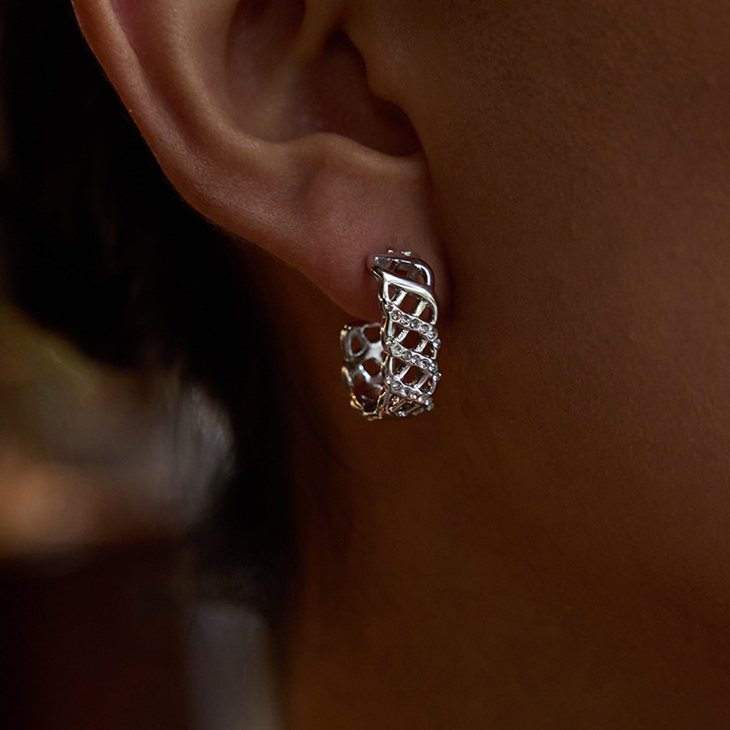 Model wearing modern gold openwork hoop earrings with rhinestones