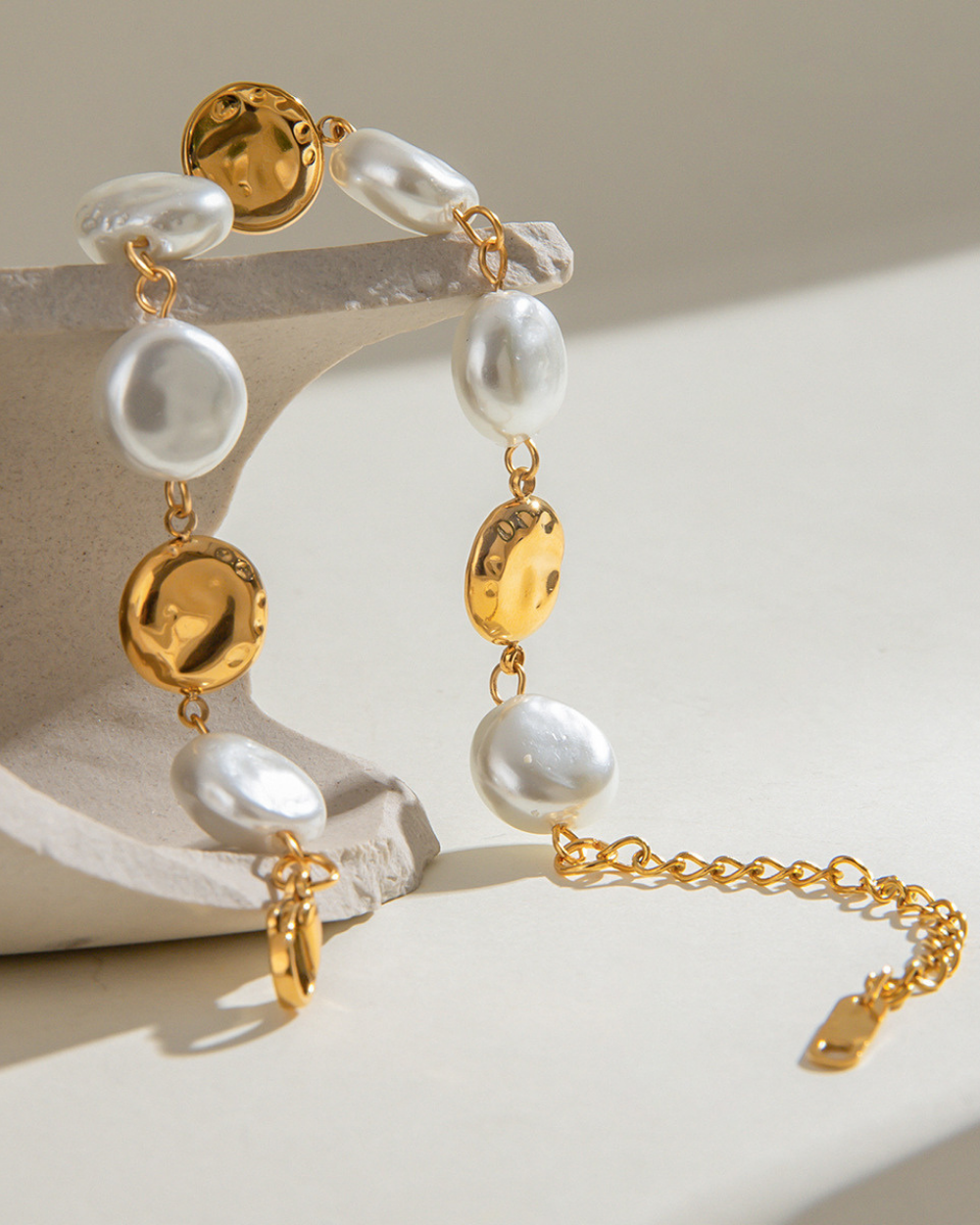 Gold and pearl bracelet on a neutral background