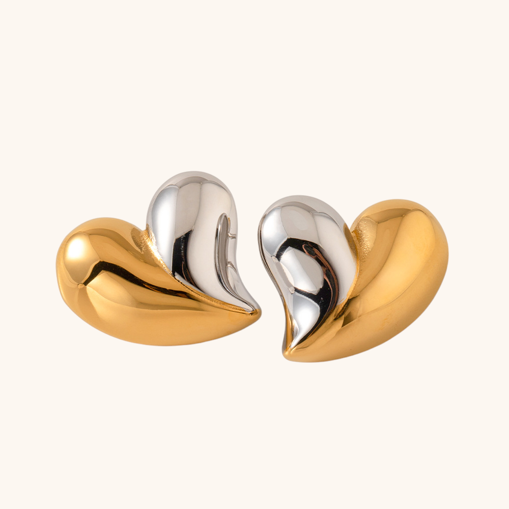 Close-up of mixed metal heart-shaped earrings in gold and silver, modern chunky design