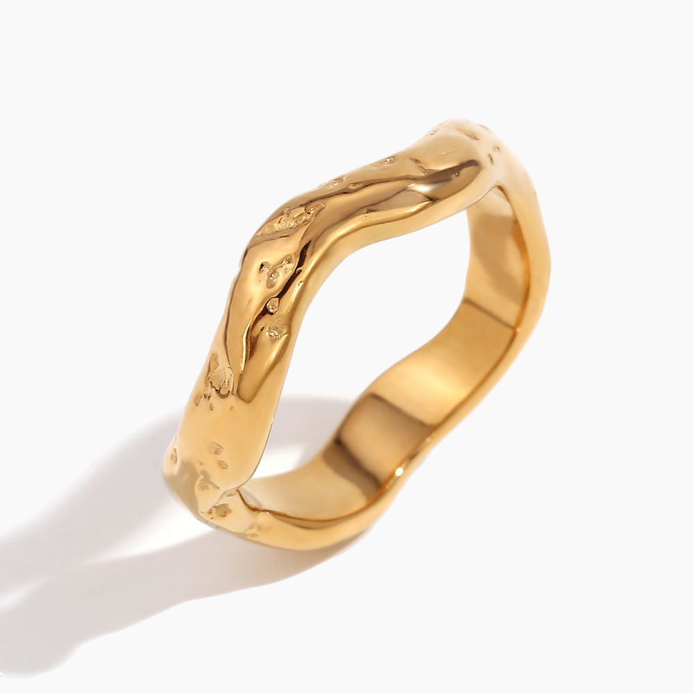 Gold ring with a textured design on a white background