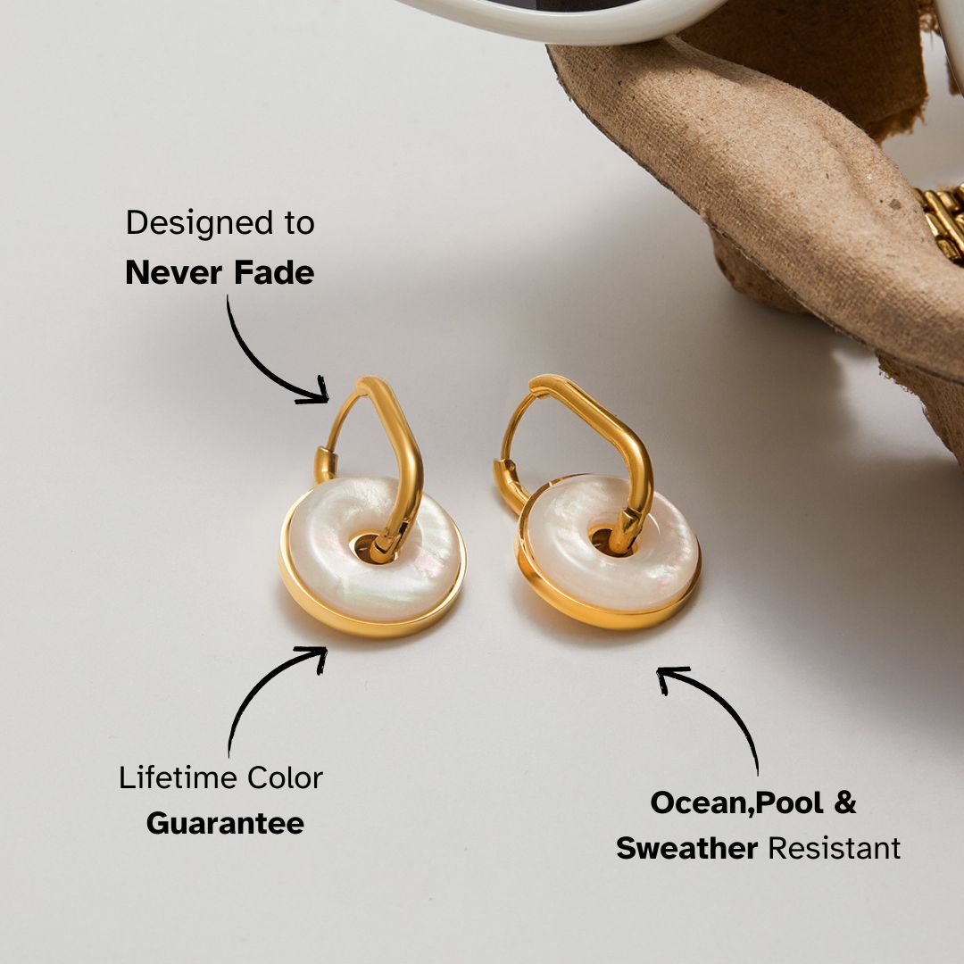 ocean-inspired white shell earrings on table with sunglasses