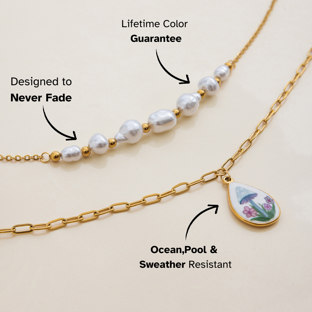 Close-up of teardrop pendant necklace with mushroom and floral enamel charm on gold chain