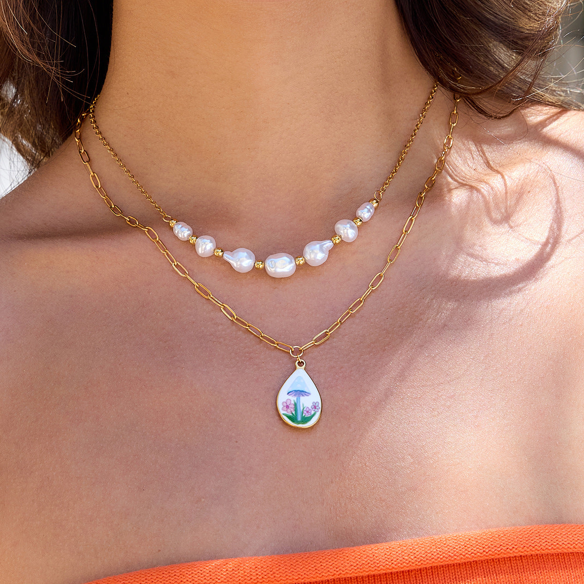 Close-up of model showing off two-layer mushroom and pearl necklace in summer light