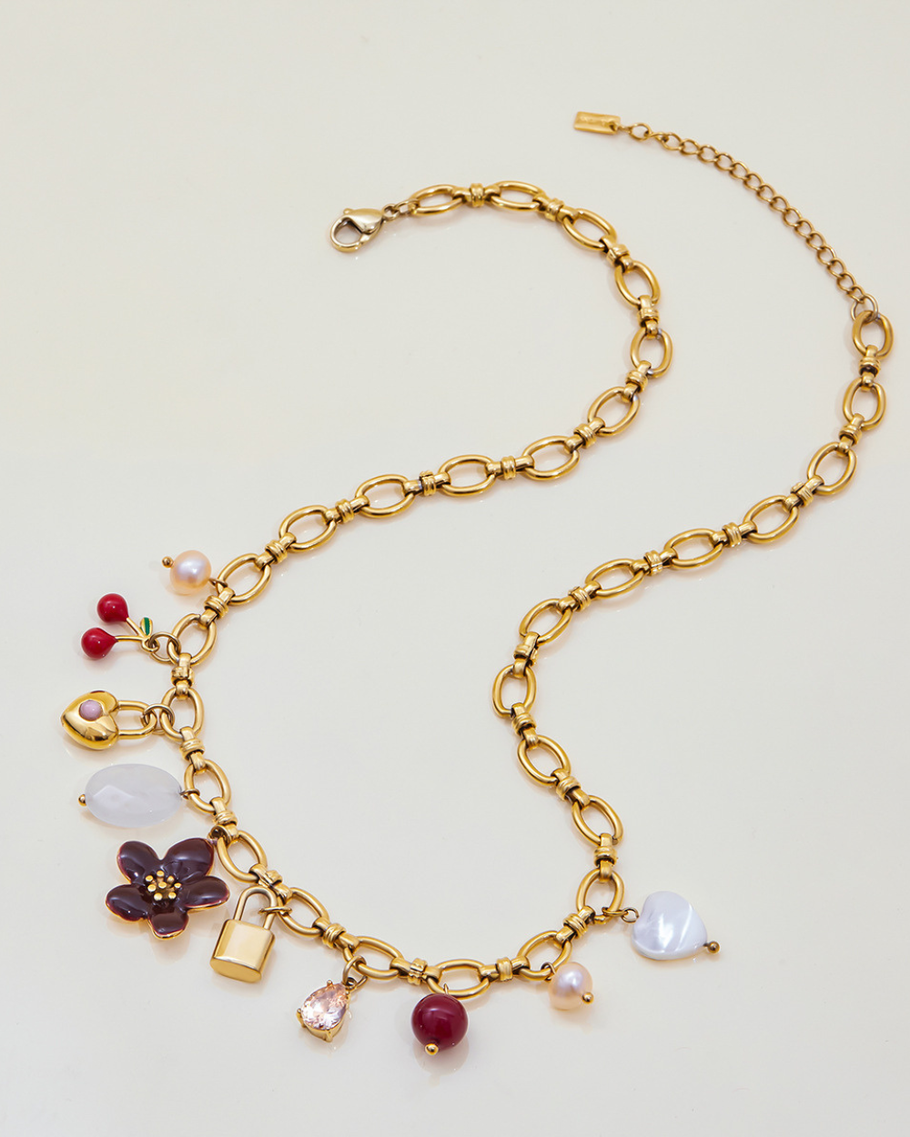 Gold bracelet with various charms on a light beige background