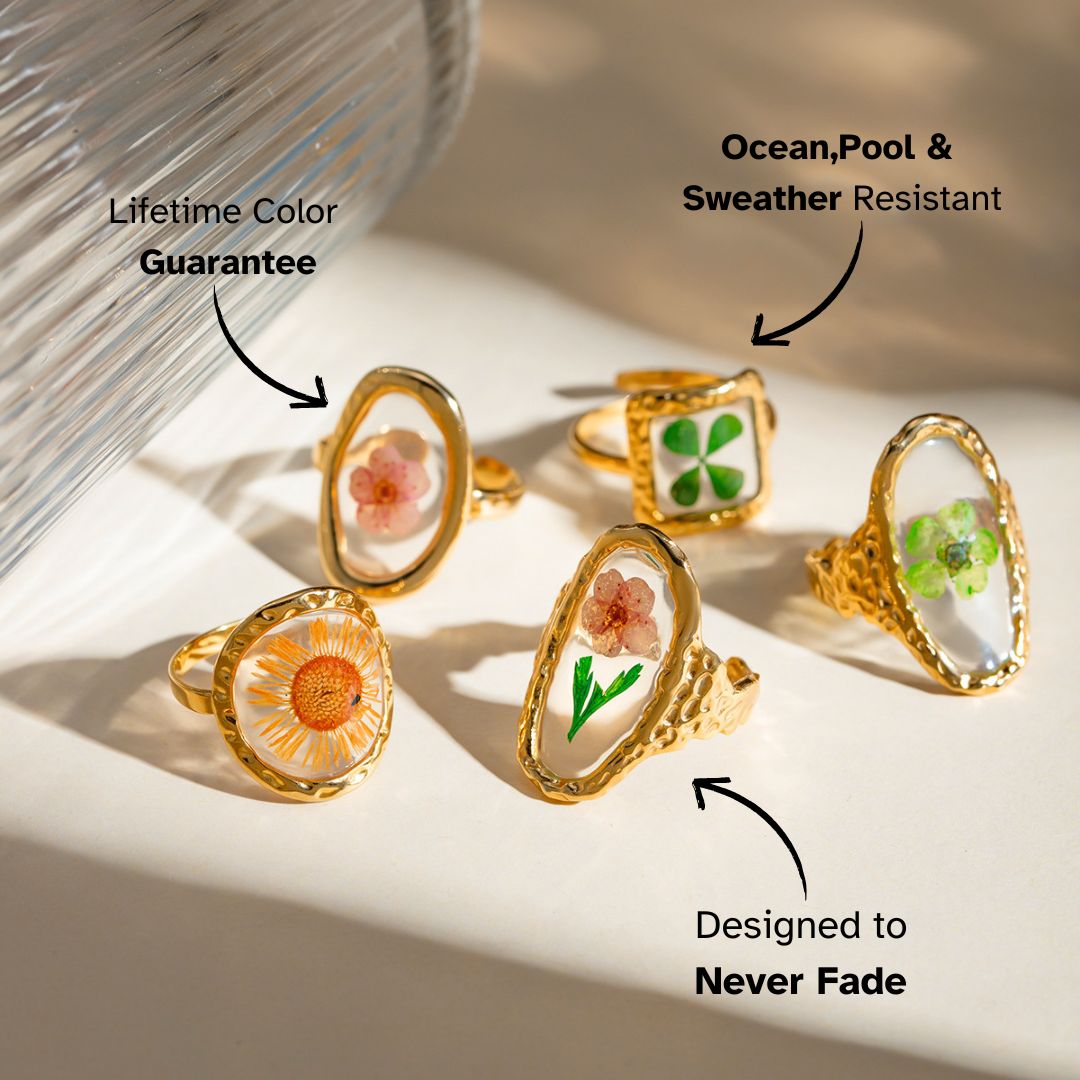 Set of 5 gold resin rings with real dried flowers styled on a pastel green background