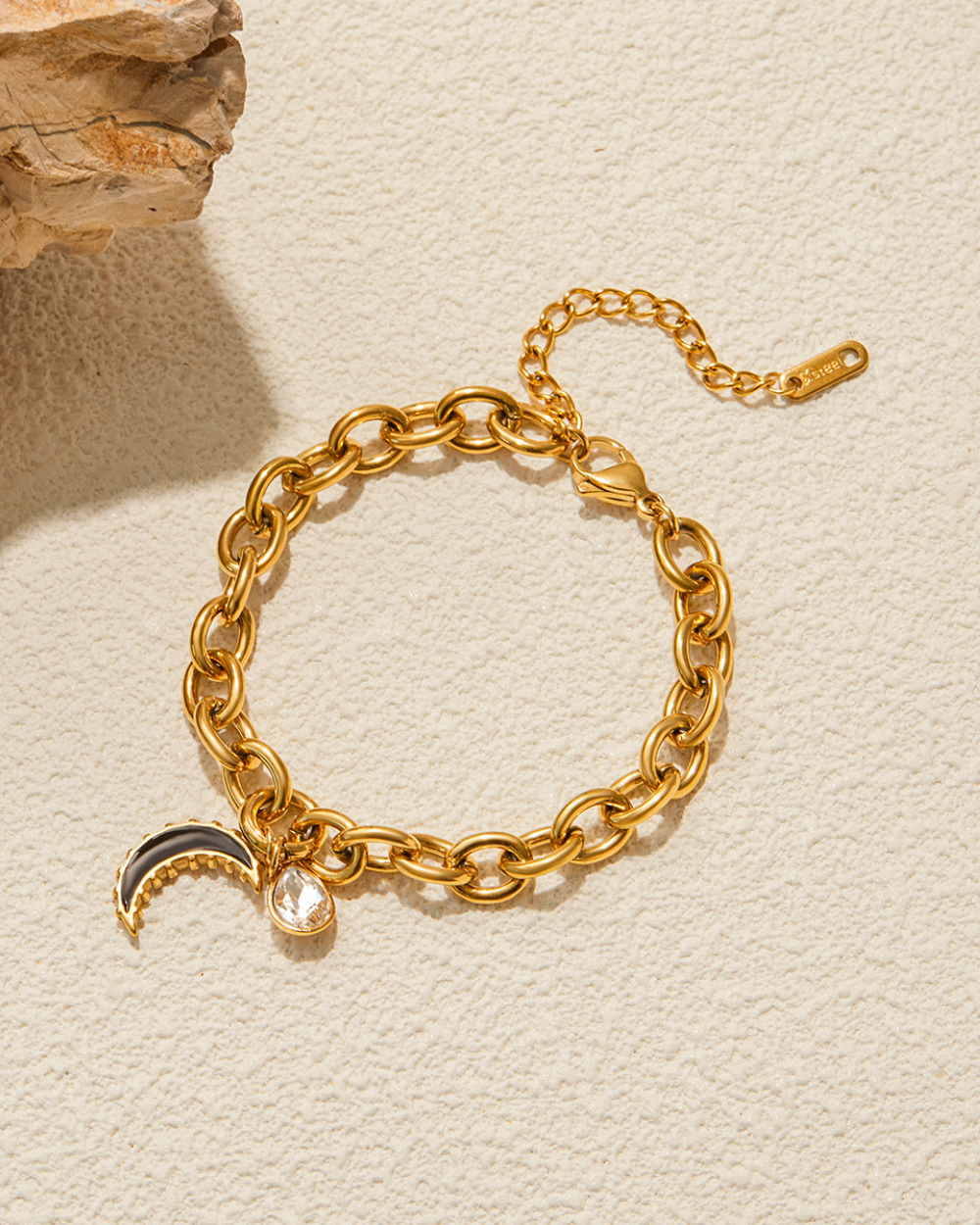Gold chain bracelet with charms on a beige background