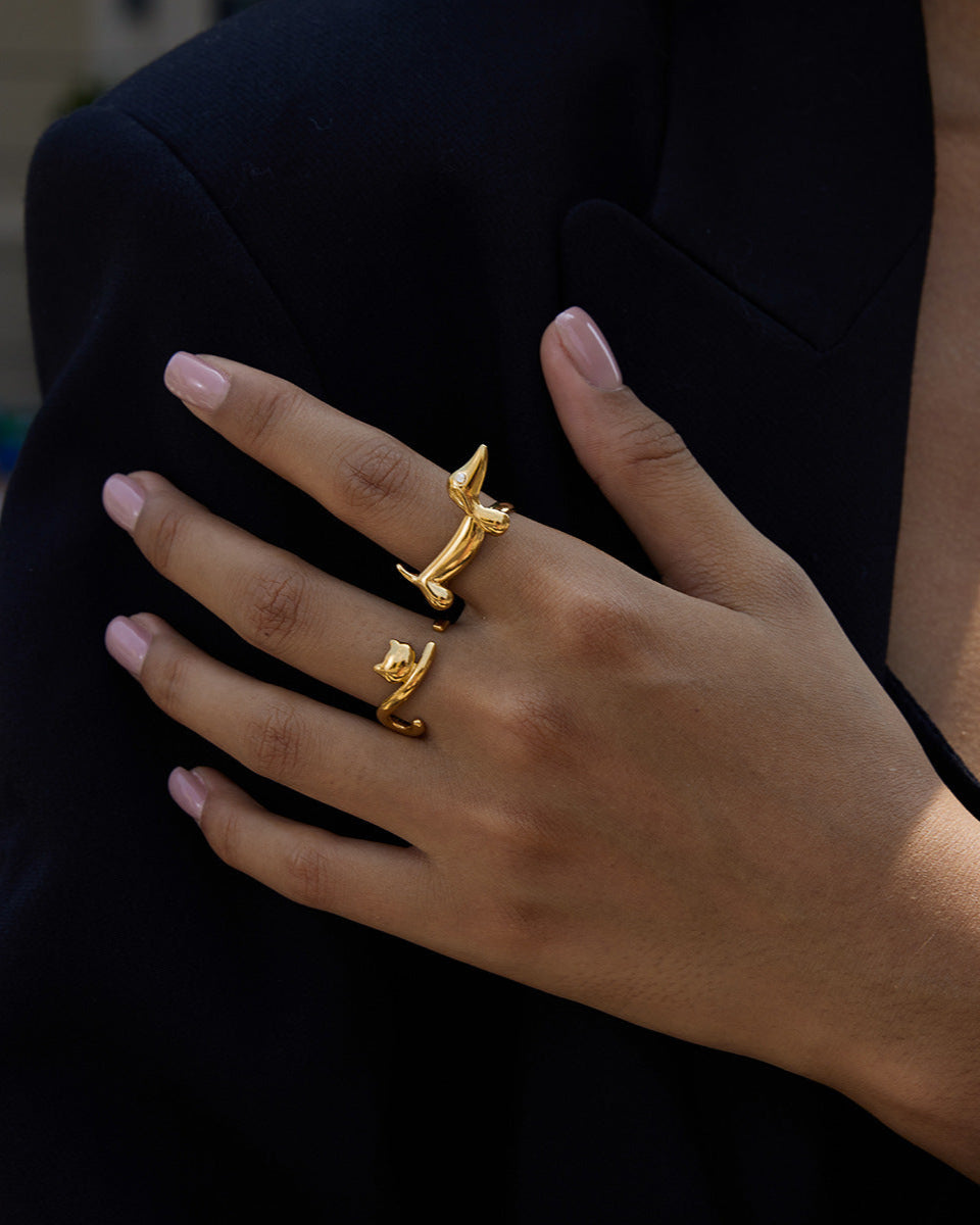 Hand wearing two gold rings with a dark background