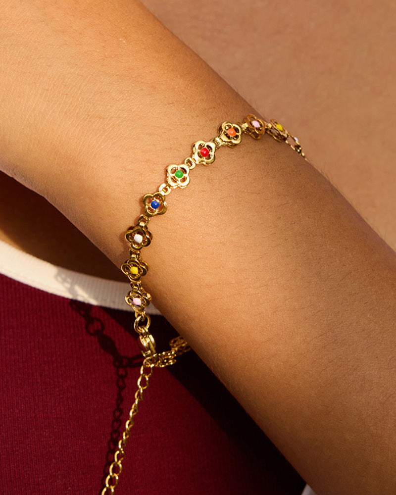 Gold bracelet with colorful stones on a wrist against a neutral background