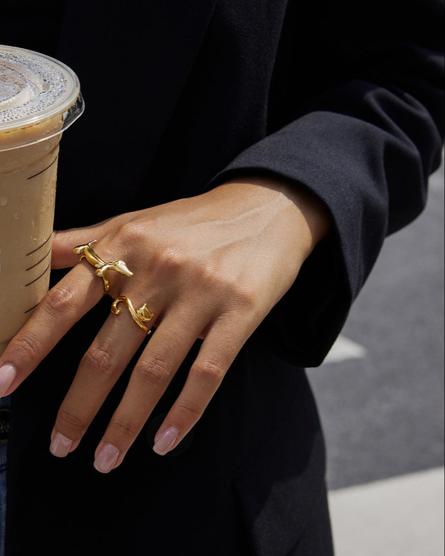 Person holding aStarbucks iced coffee with a gold ring on a blurred background