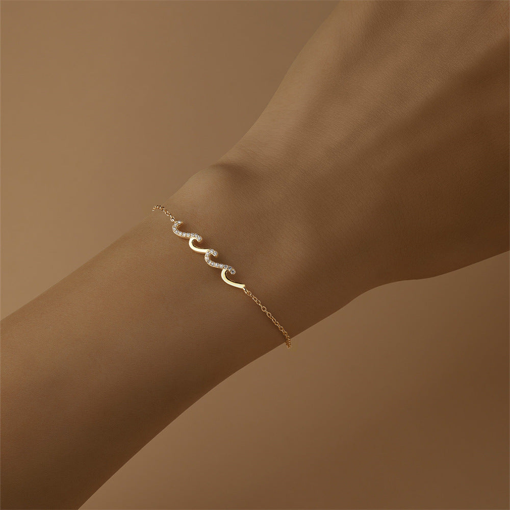 Gold wave design bracelet shown on arm with soft background