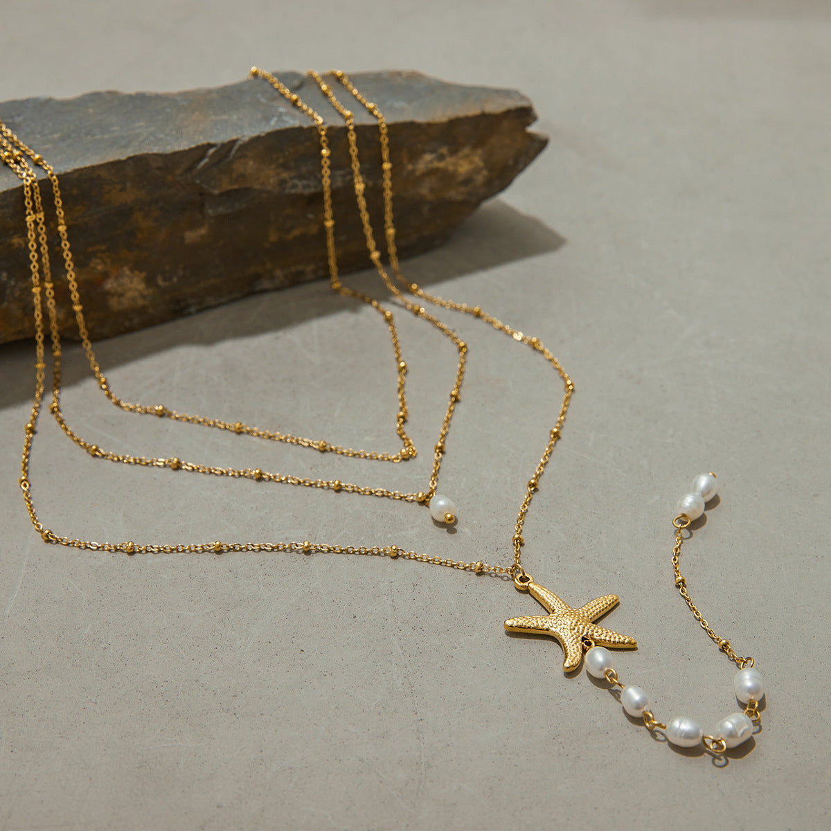 Elegant triple-layer necklace with pearls and starfish pendant styled with stone