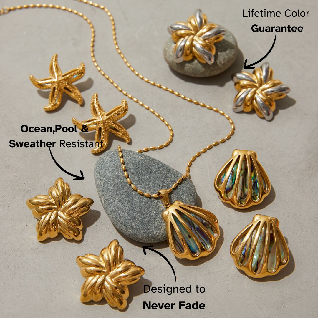 Beach-style jewelry spread on textured stone, featuring gold shell and leaf pieces