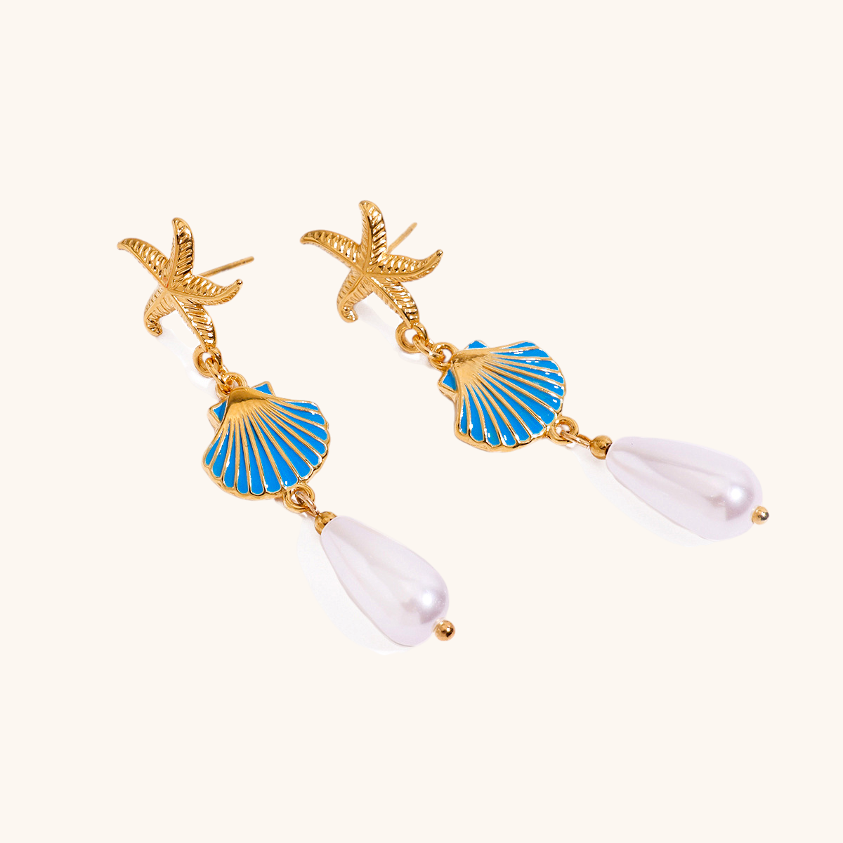 Close-up of ocean-themed starfish and pearl drop earrings on white background