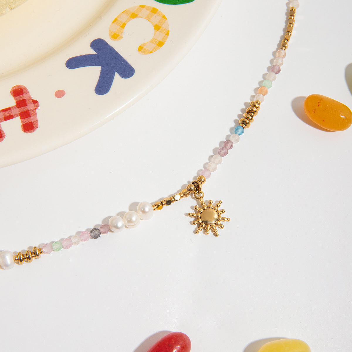 Layered jewelry set featuring pastel bead necklace and sun charm