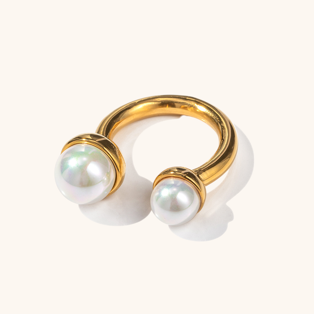 Minimalist gold ring with asymmetric pearls in soft shadow lighting