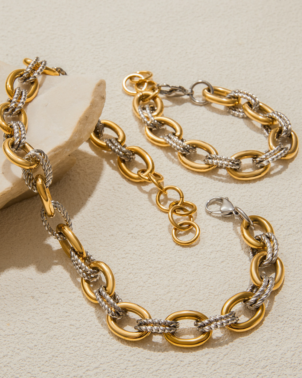 Gold and silver chain necklace on a beige background