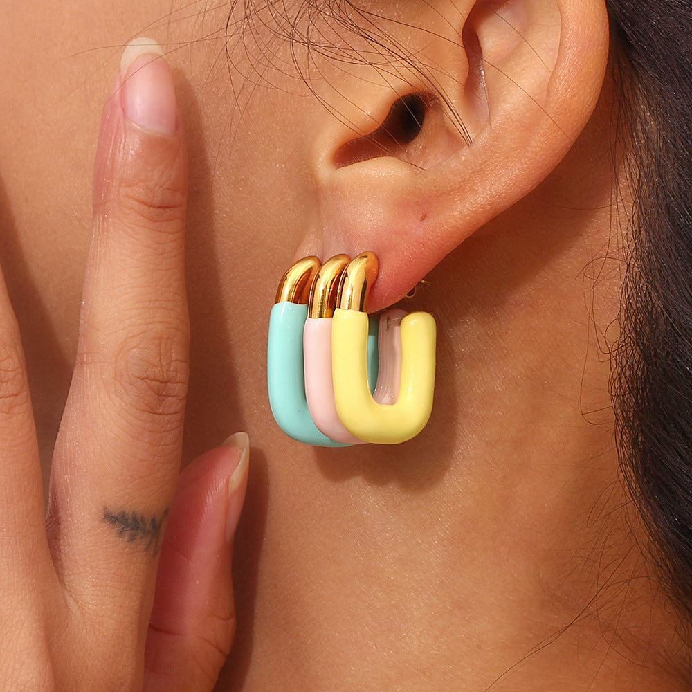 Close-up of model wearing triple-stacked pastel enamel U earrings in a vibrant, playful combo
