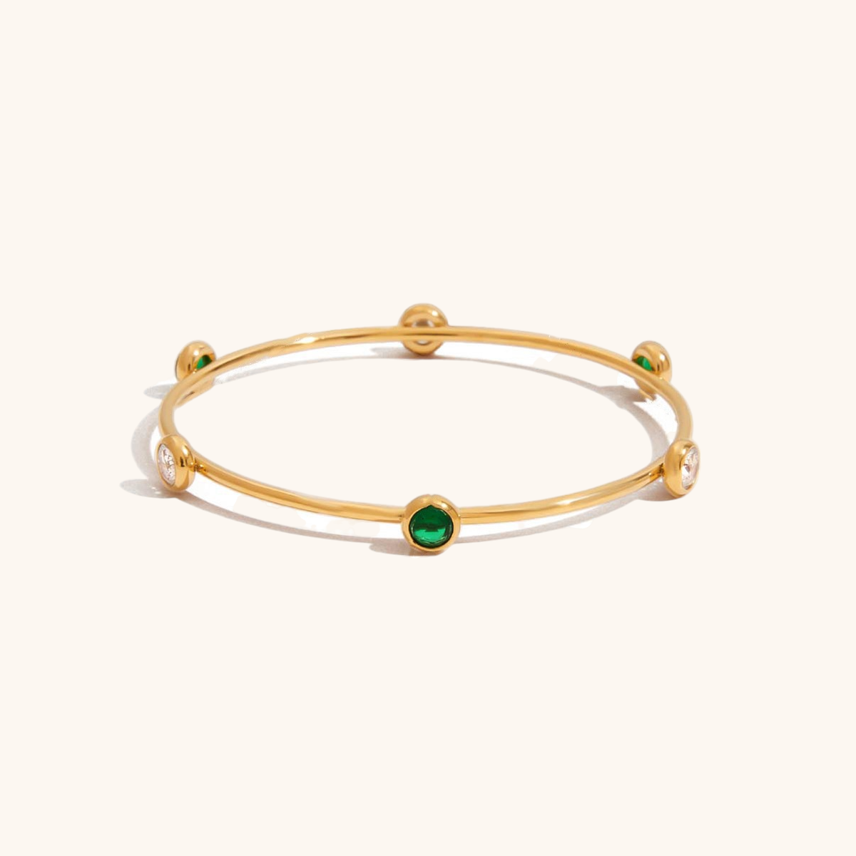 Flatlay of pearl-accented bangle on beige surface