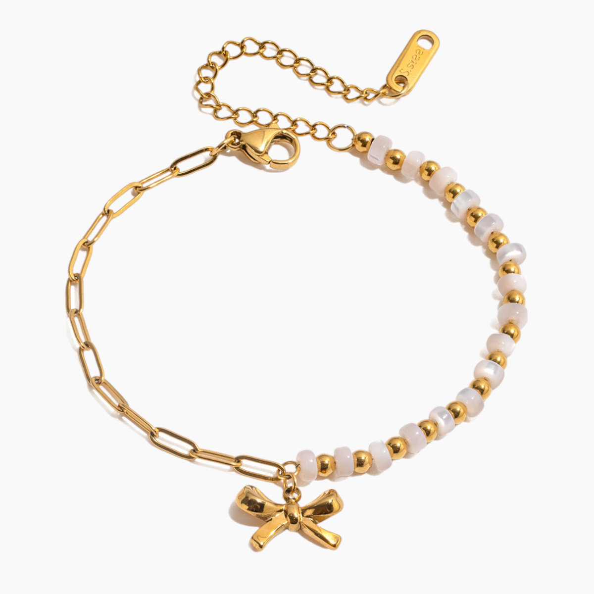 Gold and white beaded bracelet with a bow charm on a white background