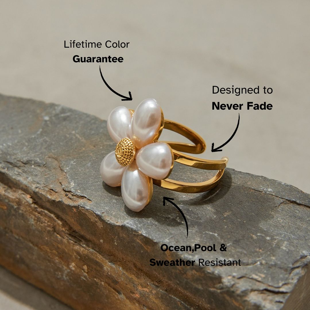 Bold gold daisy ring with teardrop pearls resting on stone surface