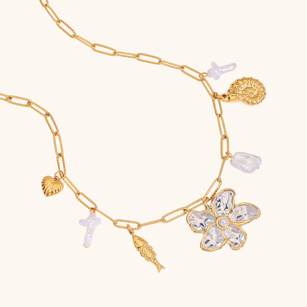 Close-up of woman wearing a gold chain necklace with floral and sea charms, matched with a soft pink outfit