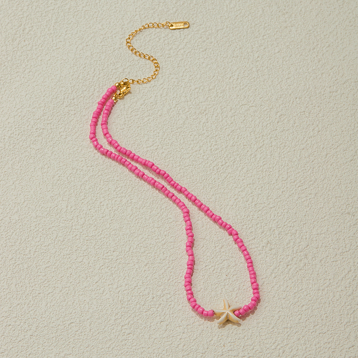 Close-up of starfish charm and pink freshwater pearls with gold accents, highlighting ocean-inspired texture.