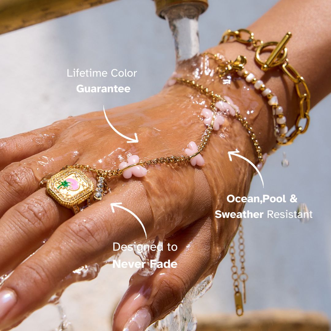 Gold pink butterfly hand chain worn under water stream, highlighting waterproof jewelry