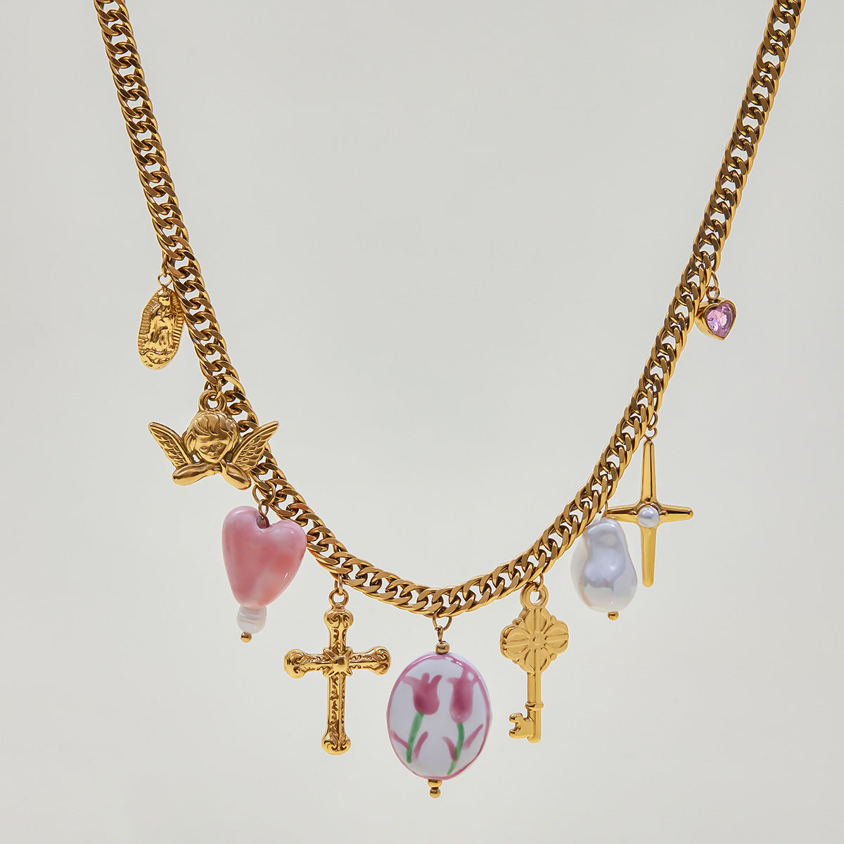 Waterproof charm necklace flat lay with tulip pendant and angel detail