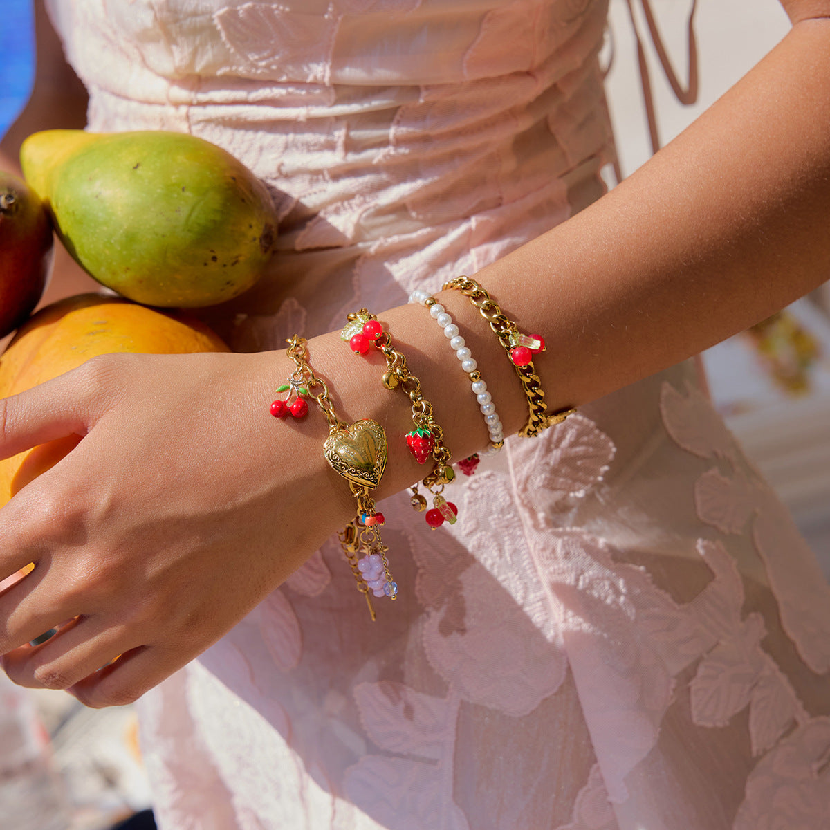 Female model wearing fruit-themed bracelet with cherries and strawberries in tropical outfit
