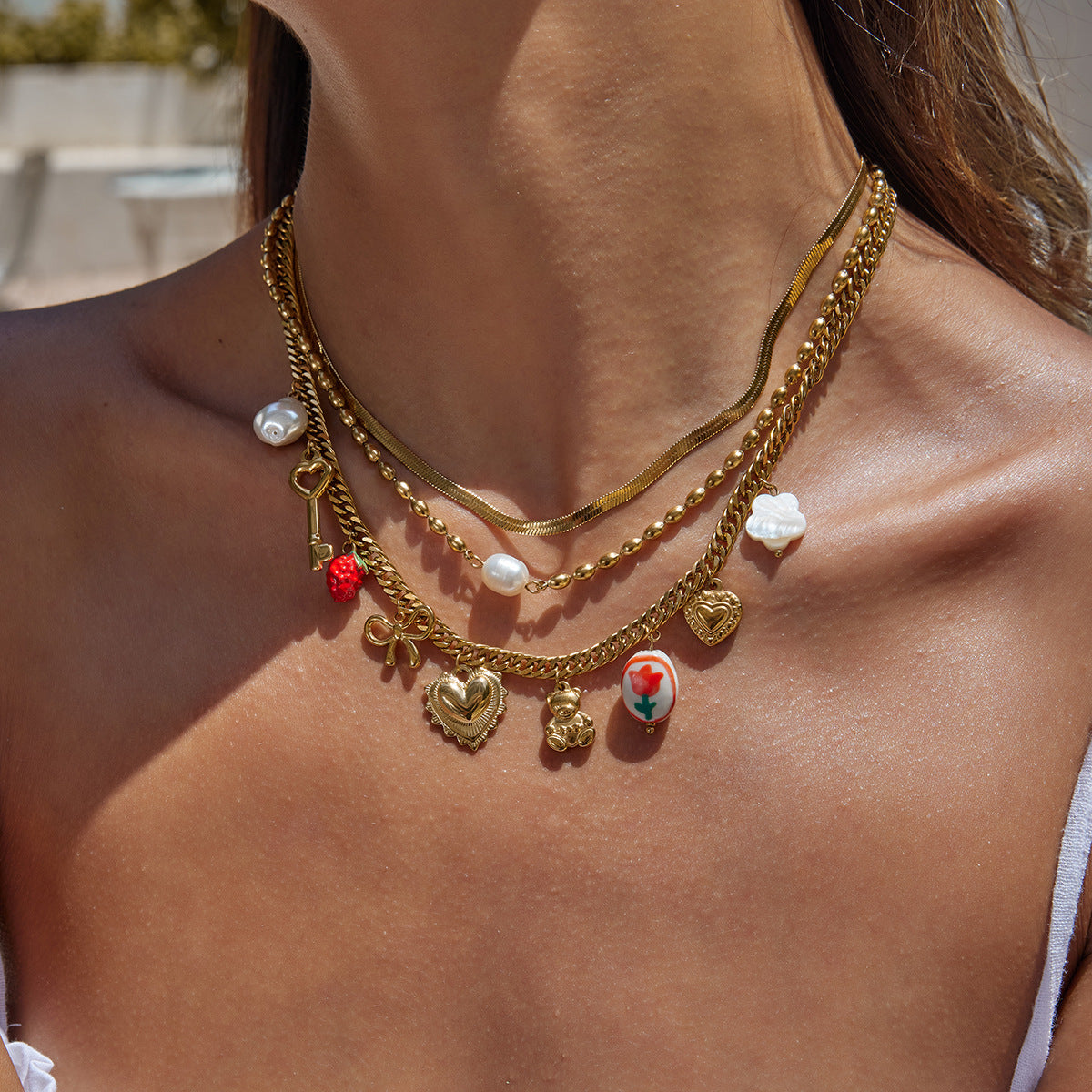 Sunlit shot of woman showcasing layered charm necklaces on skin