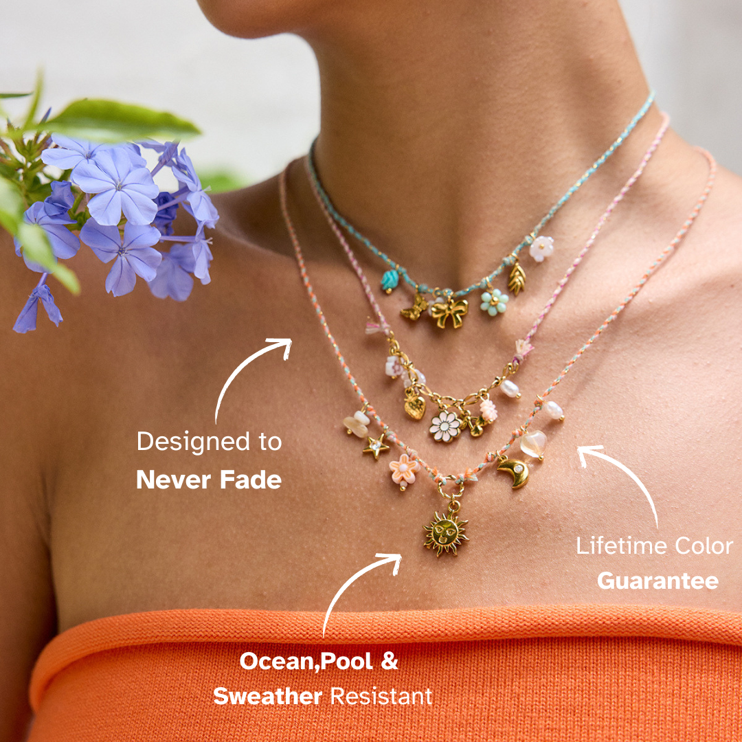 Colorful summer necklace with gold butterfly, heart, and floral charms on teal cord