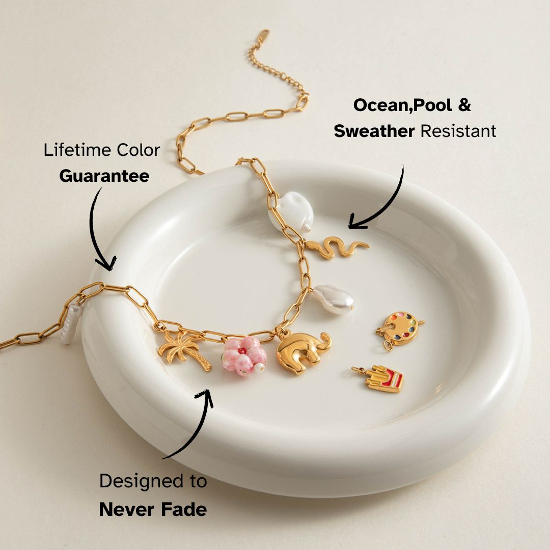 Gold charm necklace with palm tree, elephant and snake pendants, styled on ceramic dish – waterproof and tarnish-resistant