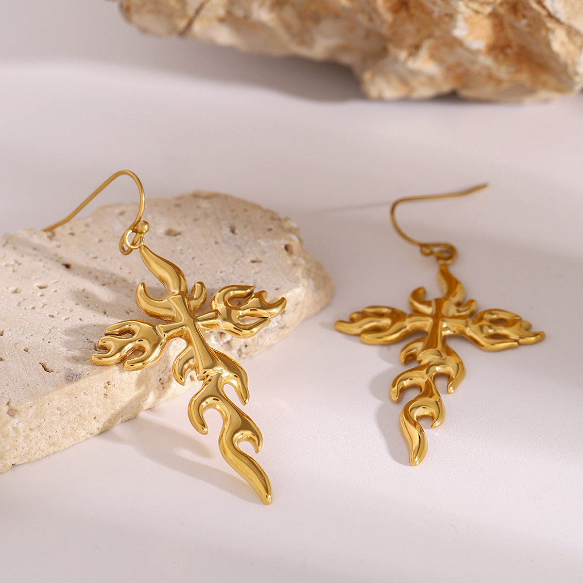 Shiny flame-shaped cross earrings with hook design, captured in daylight